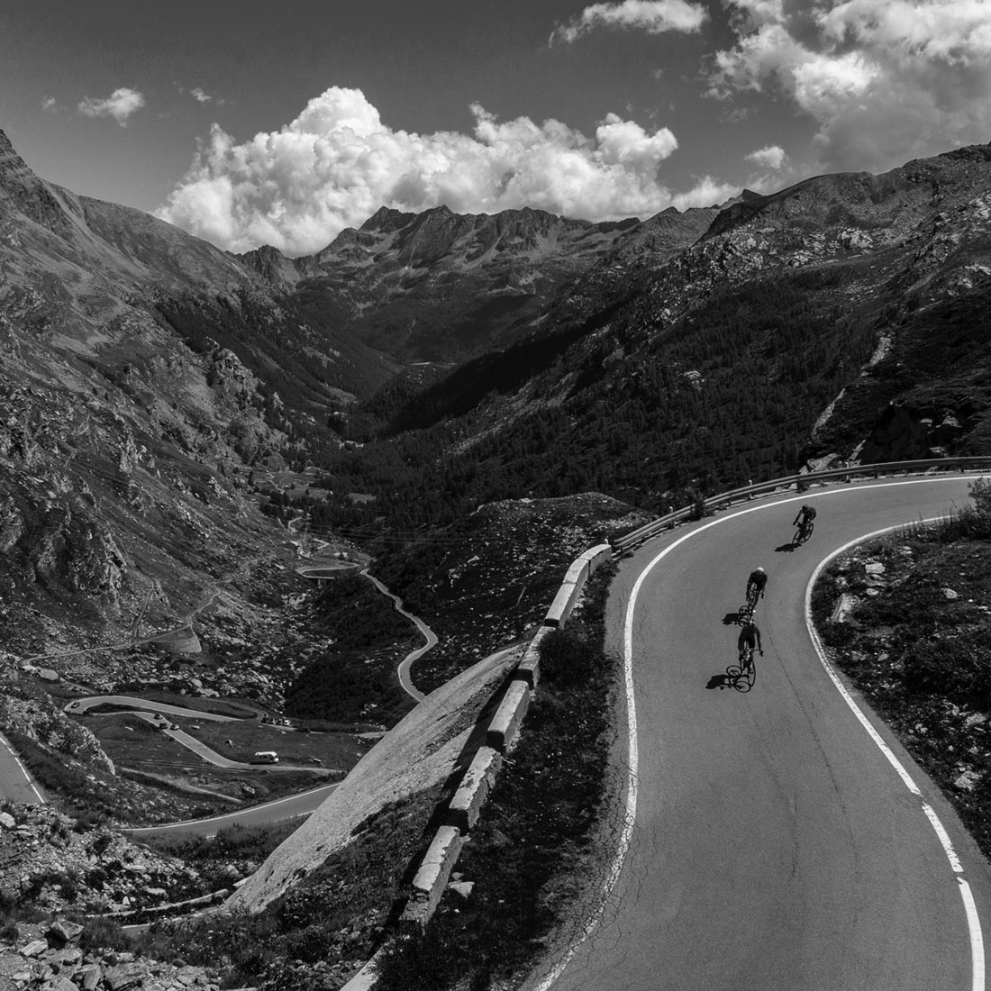 Cyclists descend from Nivolet Pass in Italy wearing black Luxa Supreme cycling jerseys.